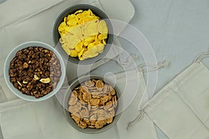 Variety of breakfast cereals and muesli in bowls on a light wooden background. Fast food. Top view. Space for text.