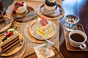 Variety of cakes and hot coffee on cafes wooden table