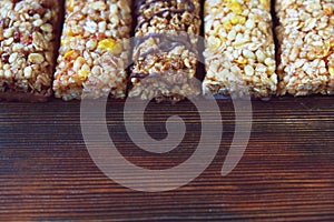 Variety of cereal bars with nuts, seeds, dried fruits and chocolate on the wooden table,top view.