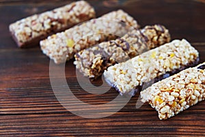 Variety of cereal bars with nuts, seeds, dried fruits and chocolate on the wooden table,top view.