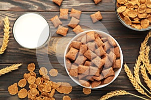 Variety of cereals in blue bowls, quick breakfast and milk on brown wooden background