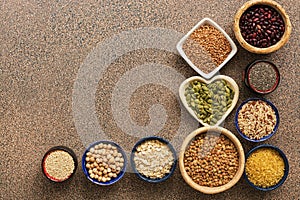 A variety of cereals, legumes, seeds on a brown stone background. Superfood set. View from above