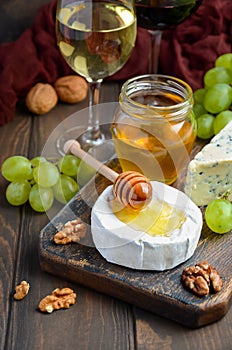 Variety of cheese with grapes, walnuts and wine.
