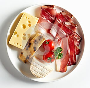 Variety of cheese, and sliced bacon on plate