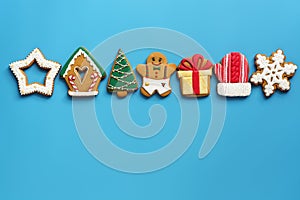 A variety of Christmas gingerbread in a row on a blue background. Top view, flat lay, copy space. The concept of the holiday