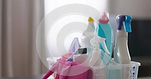 A variety of cleaning products and cloths in a plastic basket