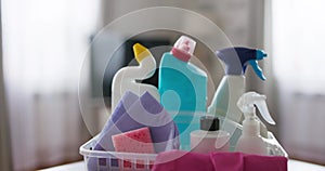 A variety of cleaning products and cloths in a plastic basket
