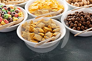 Variety of cold cereals in white bowls with spoons