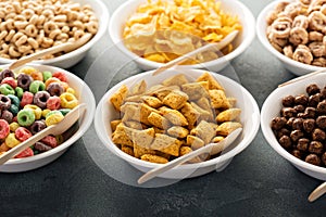 Variety of cold cereals in white bowls with spoons