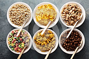 Variety of cold cereals in white bowls with spoons