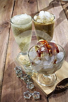 A variety of cold drinks made from fresh fruits plus shaved ice and palm sugar, placed on a wooden table with ice cubes