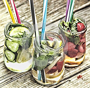 A variety of cold drinks in small bottles with pieces of fruit wooden background