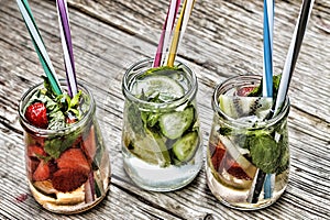 A variety of cold drinks in small bottles with pieces of fruit wooden background