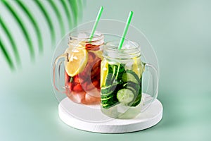 Variety of Cold Summer Drinks in Glass Jars Infused Detox Water with Cucumber Lemon and Strawberry Healthy Drink Green Background