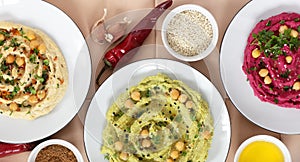 Variety of colored hummus: red, green, yellow - vegan lebanese meal, from above overhead top view, banner or background texture