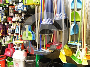 Variety of colorful brooms and brushes, household equipement in shop