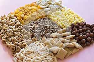 Colorful variety of cereals on pink background