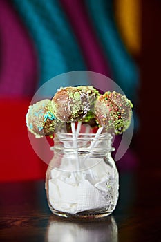 Variety of colorful Chocolate cake pops in a transparent jar. Close-up, selective focus