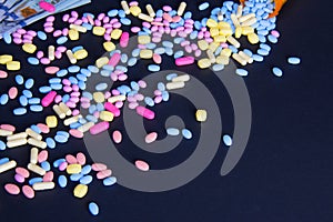 Spilled colorful pills on a black background with text space bottom right corner