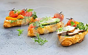 Variety of croissant sandwiches with grilled pepper, tomatoes, smoked salmon, turkey, avocado and arugula served with micro green