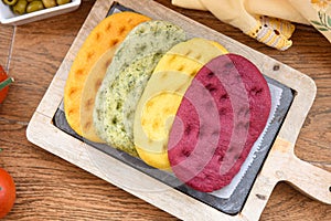 Variety of different focaccia, with pumpkin, carrot and beet, on a rustic table