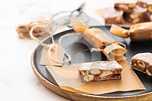 A variety of different nutty nougat in dark chocolate with roasted hazelnuts cut open to show the nougat mix on a wooden