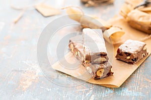 A variety of different nutty nougat in dark chocolate with roasted hazelnuts cut open to show the nougat mix on a wooden