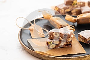 A variety of different nutty nougat in dark chocolate with roasted hazelnuts cut open to show the nougat mix on a wooden