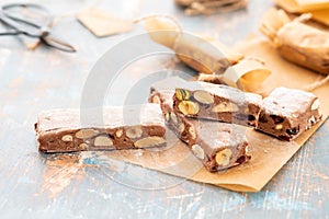 A variety of different nutty nougat in dark chocolate with roasted hazelnuts cut open to show the nougat mix on a wooden
