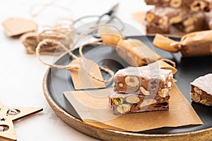 A variety of different nutty nougat in dark chocolate with roasted hazelnuts cut open to show the nougat mix on a wooden