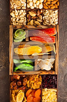Variety of dried fruits and assorted nuts in a wooden box, view from above.