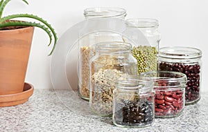 Variety of dry legumes: kidney bean, peas, green gram in glass jars uncooked on white kitchen background