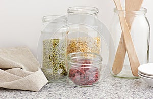 Variety of dry legumes: kidney bean, peas, green gram in glass jars uncooked on white kitchen background, zero waste, eco friendly