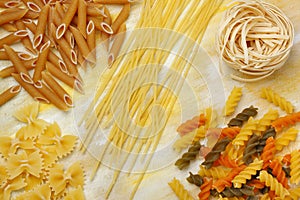 Variety of dry raw pastas over painted textile background