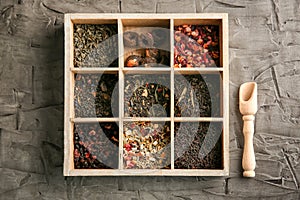 Variety of dry tea in wooden box on textured background