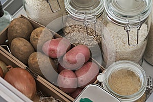 Variety of flours, rices, potatoes, onion, oil, vinegar in kitchen drawer.