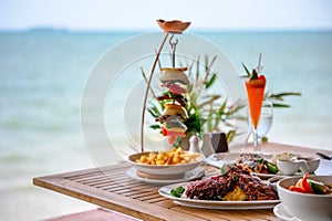 Variety of food, roasted pork ribs, beef steak, seafood and spicy soup on dining table