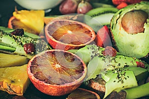 Variety of fruits, avocado, blood oranges, pineapple, kiwi, strawberries and grapes.