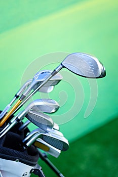 Variety of golf clubs in bag on green background