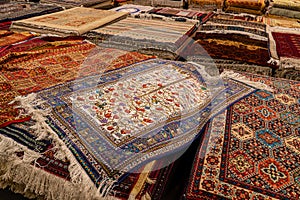 Variety of gorgeous oriental carpets in traditional carpet store in Middle East. Pile of beautiful handmade carpets on