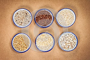 The Variety of grain rice in cup on natural brown papaer backgr