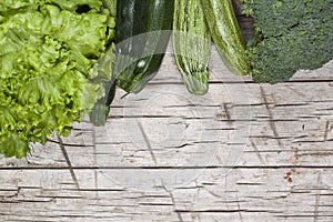 Variety of green organic vegetables on rustic wooden background