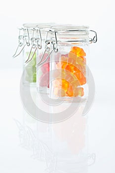 Variety of gummi bears in a preserving jar on white background