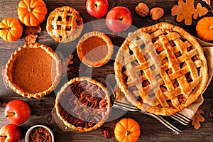 Variety of homemade autumn pies. Apple, pumpkin and pecan. Table scene over rustic wood.