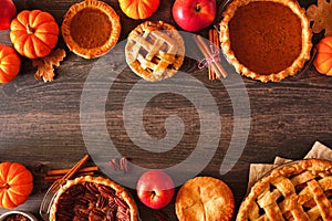 Variety of homemade autumn pies. Pumpkin, apple and pecan. Above view double border over a wood background.