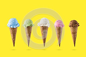 Variety of ice cream flavor in cones blueberry ,strawberry, green tea, chocolate and coconut setup on yellow background . Summer