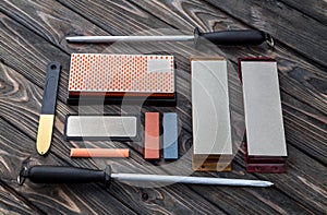 A variety of knife sharpeners. Sharpening stones and devices on a wooden background. Grinding stones