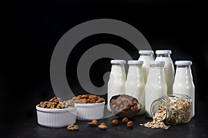 a variety of lactose-free milk from nuts and grains in glass bottles. dark vegan concept with a milk drink made from hazelnuts,