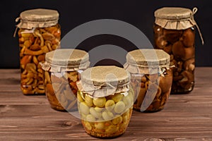 Variety of marinated and canned mushrooms in glass jars.
