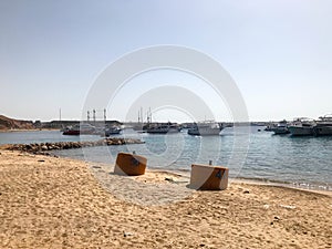 A variety of motor and sailing ships, boats, cruise liners stand on a dock in the port against the background of the blue sea and